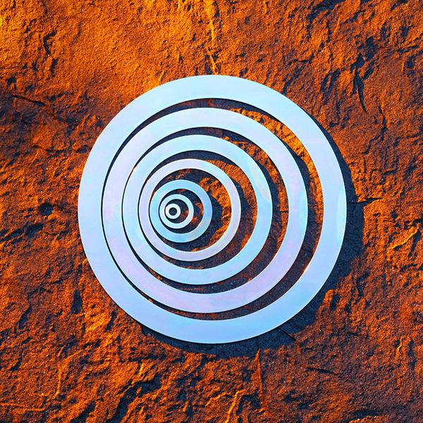 Unterlegscheiben Unterlegscheiben in verschiedenen Größen, das auf einer strukturierten, orangefarbenen Oberfläche platziert ist. Die Ringe sind in einem hellen, glänzenden Material gehalten, das Licht reflektiert.