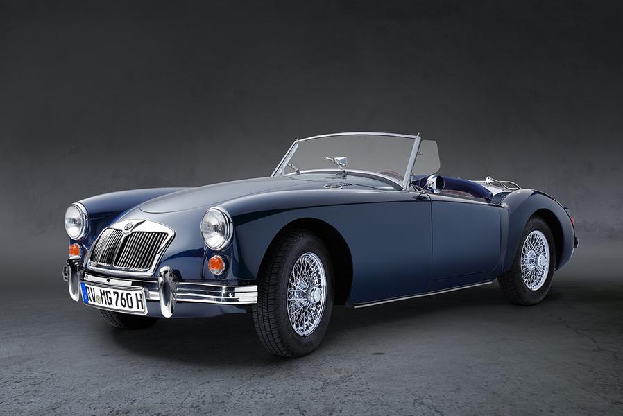 Ein blauer Oldtimer-Cabriolet mit offenem Verdeck steht auf einer neutralen, grauen Fläche. Die glänzenden Felgen und der Charme des klassischen Designs heben sich von der dunklen Hintergrundfarbe ab.